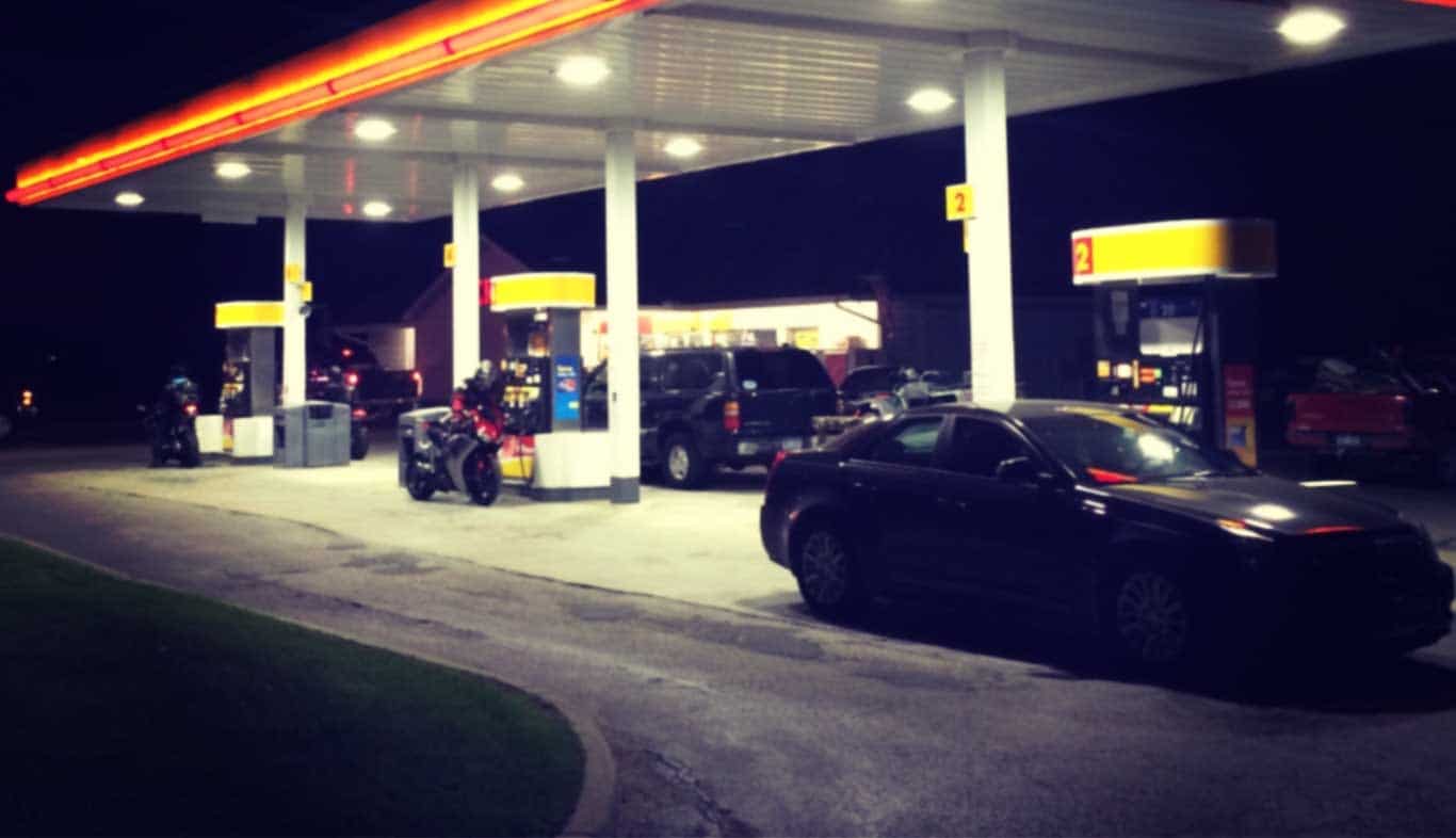 AKT Peerless cars and motorcycles at gas station at night