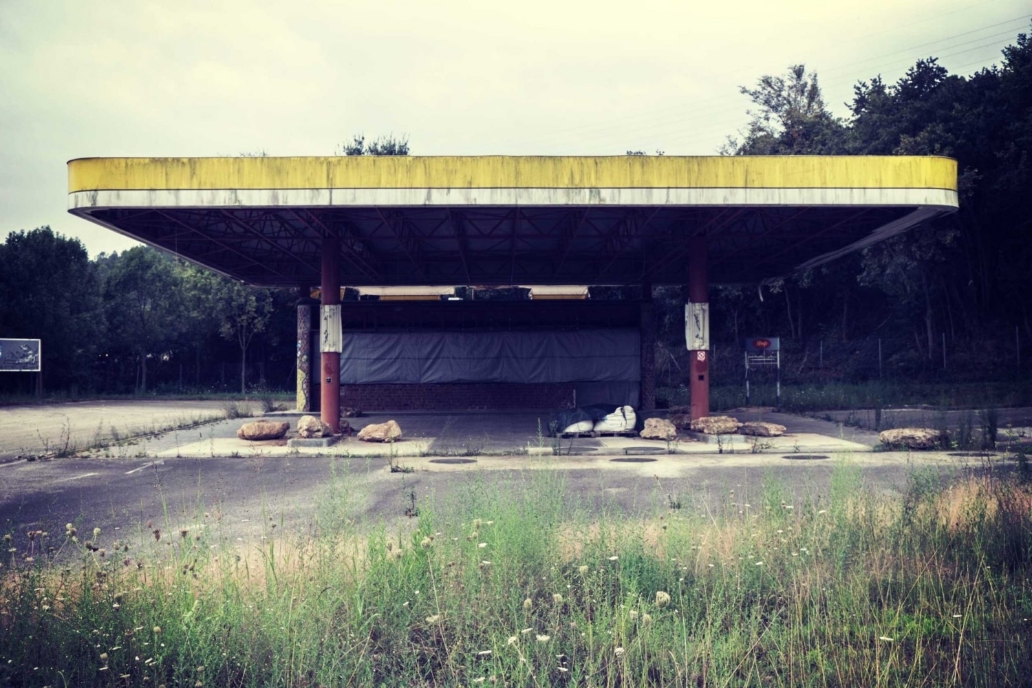 photo of old empty abandoned gas station that is overgrown with grass