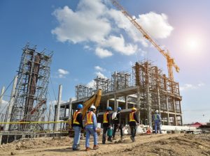 group of construction workers in hard hats at construction site crane