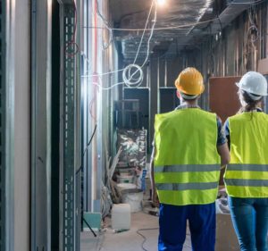 Man and Woman in hi-vis vests and hardhats in construction zone